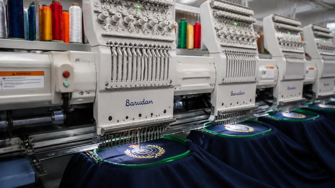 Computerized Tajima multi-head embroidery machine stitching insignia on knit panels